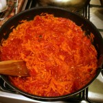 В морковку добавляем помидоры и готовим, разминая помидоры лопаткой